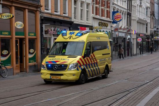 Een gele ambulance rijdt door de Regulierbreestraat in Amsterdam