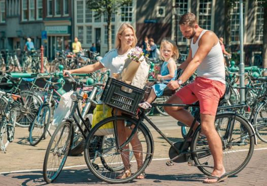 Jonge ouders op de fiets met kindje voorop in Amsterdam